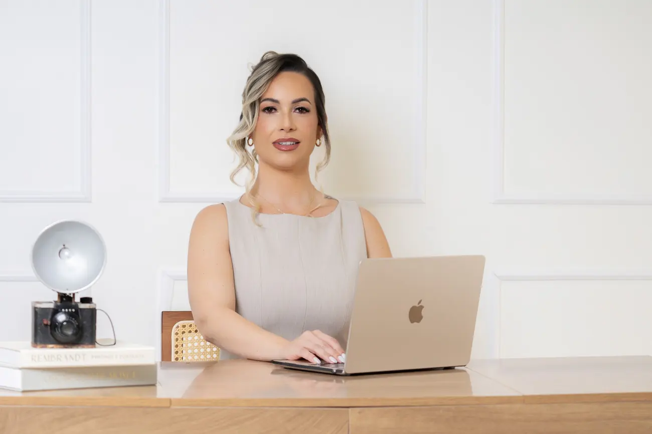 Yaima Clausell trabajando con su computadora en un escritorio de madera clara.